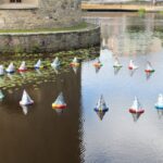 A group of paper boats floating on top of a lake