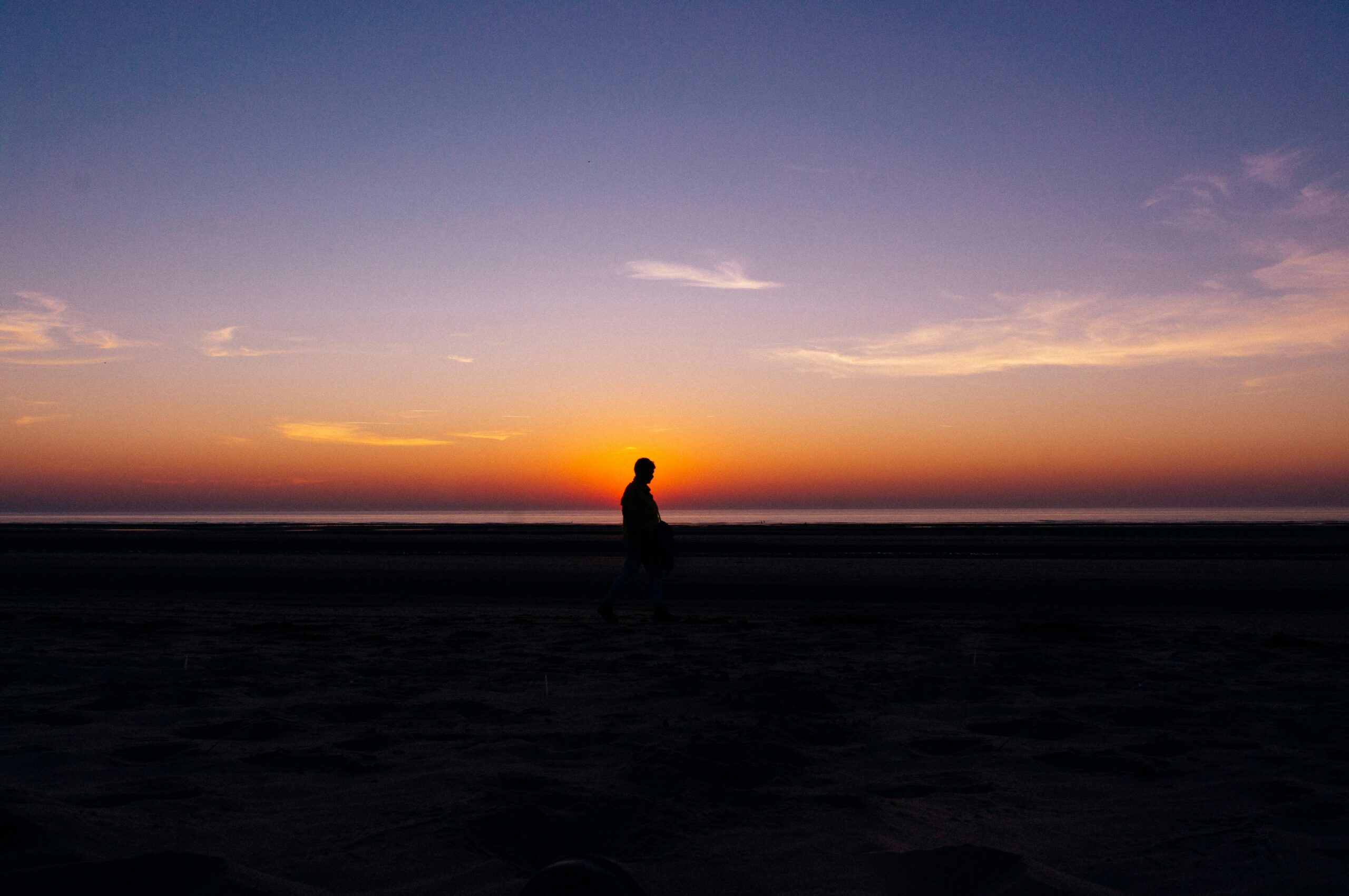 a person walking on a beach at sunset