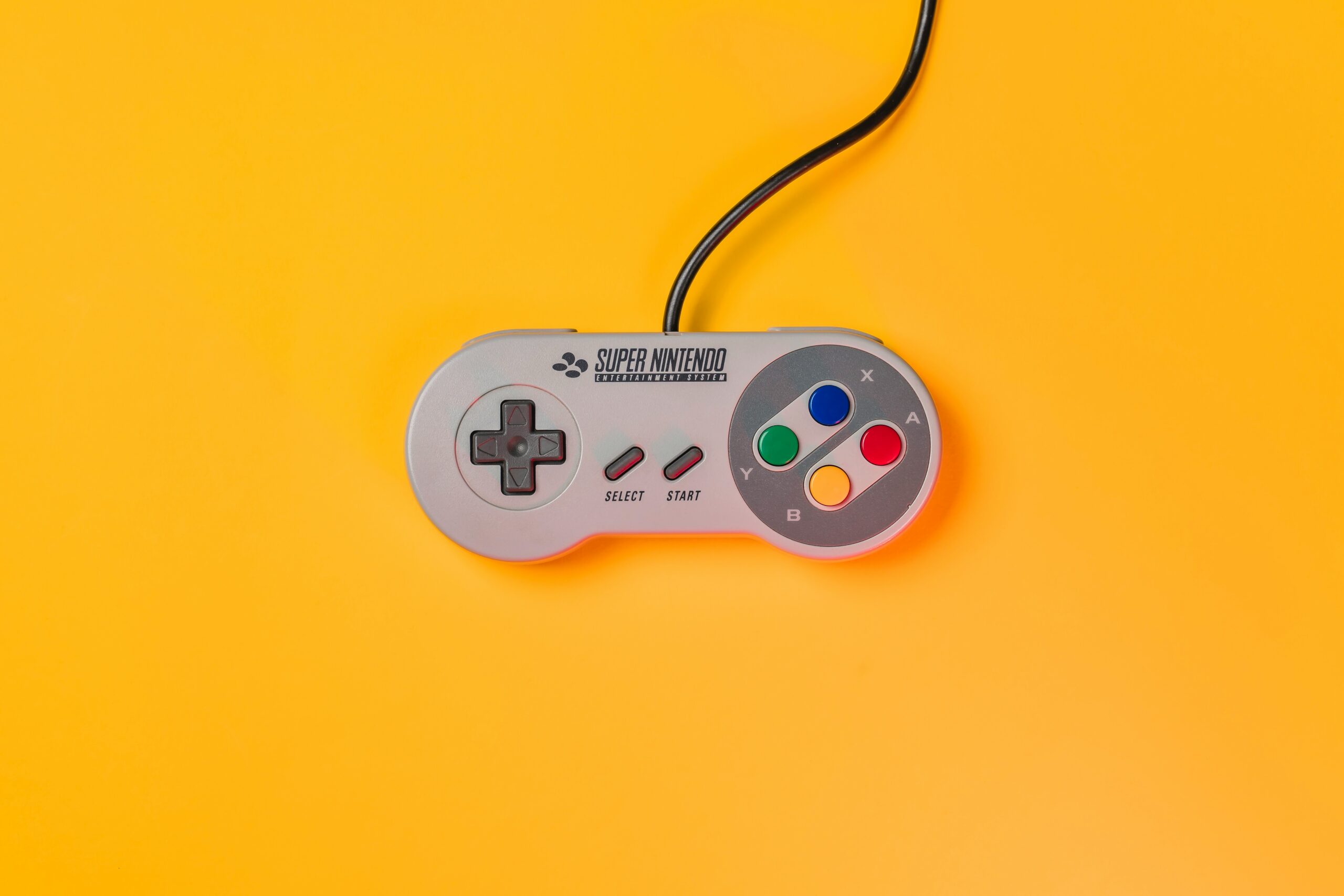 white nintendo game controller on yellow surface